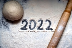 Baking flour and number 2022 on blackboard. Top view. rolling pin, flour and shape new year.New year ornament food background. Home made.