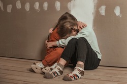 two little sister girls hugged and crying in the attic of the house, they are scared. domestic violence and a dysfunctional family with underage children