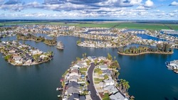 Drone photo over a water community in Discovery Bay, California with rows of houses along water fronts and blue water and blue sky