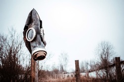 old soviet tattered gas mask hanging on a pole in an abandoned area