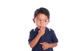 Child asking for silence, isolated on white background. Latin boy asks for silence with finger on mouth.