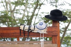 Jewish religious objects together on a wood on a background full of nature. kipa, tallit, Tzitzit, tefillin, hat.