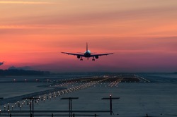 passenger plane is landing in the airport runway at early morning at sunrise time in the frosty winter air
