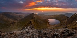 Beautiful vibrant sunrise overlooking Red Tarn and Ullswater from the summit of Helvellyn mountain range. Wide panoramic Lake District views.