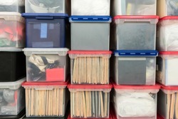 Stacked plastic file storage boxes with folders, binders and miscellaneous items.  