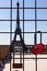 Red love lock on iron grid, with two lovers' names and Eiffel Tower on background, Paris