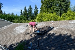 Middle aged caucasian woman installing a skylight cover on a residential house skylight, preparation for summer
