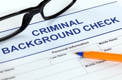 Criminal background check application form with glasses and ballpoint pen.