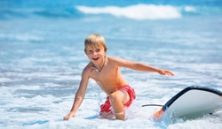 Happy boy - young surfer learning ride, jump from surfboard with fun, run to beach. Active family lifestyle. Kids surf lessons, outdoor water sport activity in surfing camp. Summer vacation with child
