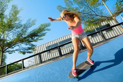 Skateboarder in action. Young woman making trick on surf skate longboard in outdoor skatepark bowl. Surfskate and skateboard riding lessons at summer sport camp. Teens weekend recreational activities.