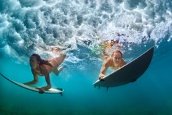 Group of active girls in action. Surfer women with surf board dive underwater under breaking big wave. Healthy lifestyle. Water sport, extreme surfing in adventure camp on family summer beach vacation
