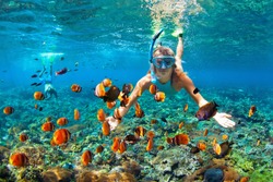 Happy family - couple in snorkeling masks dive deep underwater with tropical fishes in coral reef sea pool. Travel lifestyle, outdoor water sport adventure, swimming lessons on summer beach vacation