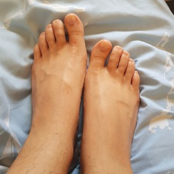 Unpainted toes barefoot on a blue background bedsheets. feet with veins and long toes. Beautiful and female feet 