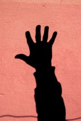 Shadow of the human arm on the pink cement wall.