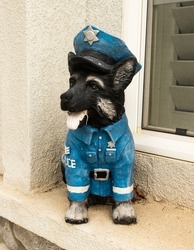 Aged sculpture of a black german shepherd puppy wearing a police officer uniform