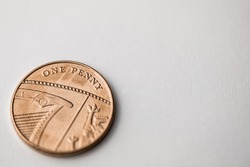 Close up of a single one penny copper coin on a white background shot at an angle.