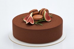 Chocolate mousse cake decorated with pieces of figs, macaroons  and rosemary on white background
