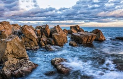 Waves beat against the coastal sea rocks. Coastal sea rocks. Sea rocks view