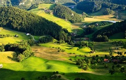 A village in a green mountain valley. Mountain green valley village panorama. Village in mountains. Mountain green hills village