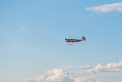 Small retro airplane, light aircraft flying in blue cloudy sky and doing stunts at Air Show. Performance, extreme, aerobatic and sport concept
