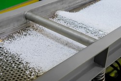 Polyethylene or propylene pellets - recycled plastic granules on conveyor belt, shale shaker of waste plastic recycling machine. Environmental protection, separation, automated technology concept