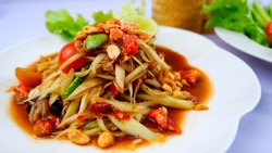 Somtum, traditional Thai food Garnished with papaya, tomatoes, green beans and peanuts, garnish with lime salad on a white plate. side view