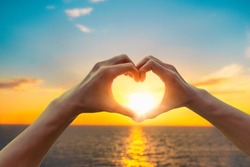Female hands in the form of heart against sunlight in sunset sky on beach summer. Hands in shape of love heart, Love concept.