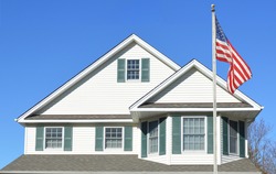American Flag pole Suburban Home Roof Windows Sunny clear blue sky day residential neighborhood USA