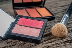 A palette of double blush for the face behind triple blush palette and brush .Make-up products