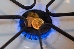 Gas flame of a gas stove burner with Euro coins. Blue natural gas blaze.