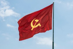 Large communist flag floating in the wind with a blue sky background