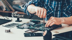 Computer repair shop. Engineer performing laptop maintenance. Hardware developer fixing electronic components. PC technology