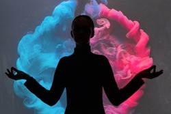 Double exposure silhouette. Meditation therapy. Harmony balance. Black contrast shape portrait of peaceful woman in yoga pose on blue pink smoke cloud background.