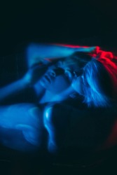 Nightmare anxiety. Night terror. Sleep disorder. Phobia paranoia. Blur double exposure dark silhouette of disturbed woman suffering from panic attack in red blue neon light.