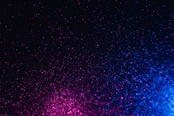 Color glitter overlay. Blur sparkles. Bokeh light. Night sky stars reflection. Neon blue magenta pink grain texture glow on dark black shimmering abstract background.