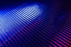 Futuristic background. Grooved texture. Fluorescent glow. Neon blue magenta pink color gradient light glare on dark ribbed abstract overlay.