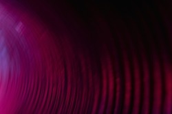 Blur neon background. Curved texture. Lens flare. Glowing fluorescent tunnel. Defocused magenta pink color light reflection on dark bent lines pattern abstract overlay.