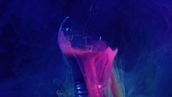 Ink water drop. Broken light bulb. Fantasy energy. Neon pink blue color smoke haze floating in cracked lamp glass on dark mist texture abstract art copy space background.