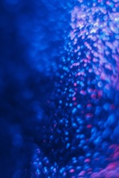 Bokeh light flare. Defocused neon glow. Ultraviolet radiance. Blur fluorescent navy blue pink color circles glare grain texture on dark futuristic abstract background.