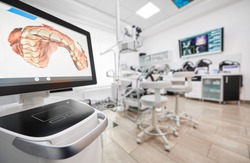 Snapshot of empty clean dental office. Interior of modern dental clinic. Computer screen with high precision digital jaw print on it on foreground.