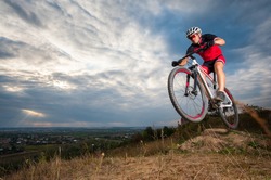 Male mountain biker jumping against blue evening sky. Low angle portrait. Extreme sport donwhill cyclist