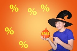 A child in a hat holds an orange pumpkin. Happy scary Halloween, baby. The concept of sales