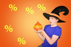 A child in a hat holds an orange pumpkin. Happy scary Halloween, baby. The concept of sales