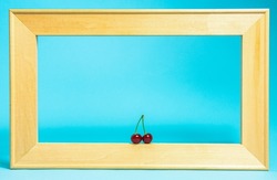 a wooden frame with a pair of cherries in the lower part on a blue background