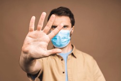 Protection against contagious disease, coronavirus, covid-19. Man wearing hygienic mask to prevent infection, airborne respiratory illness such as flu, 2019-nCoV. Isolated over beige background