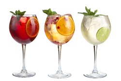 Alcoholic and non-alcoholic refreshing cocktails with mint, fruits and berries on a white background. Three cocktails in glass glasses on a long leg. Isolated.