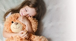 Little Girl hugs her favorite toy. This is a big teddy bear. Love and tenderness. Happy childhood concept. High quality photo. A gift for a birthday or other holiday. 