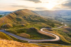 Beautiful winding road and hills at sunset in the Peak District - Landscape view with golden light in the UK - Nature and travel concepts, background ready image