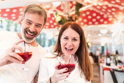 Happy people couple or friends enjoying a drink in Barcelona and laughing - Adult man and woman together at a bar in Barcelona enjoying a glass of sangria and having fun - Love and lifestyle concepts