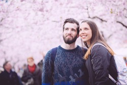 Young hipster couple portrait in Stockholm with cherry blossoms at Kungstradgarden, the swedish for Kings Garden. Love and friendship concepts with a hipster theme.